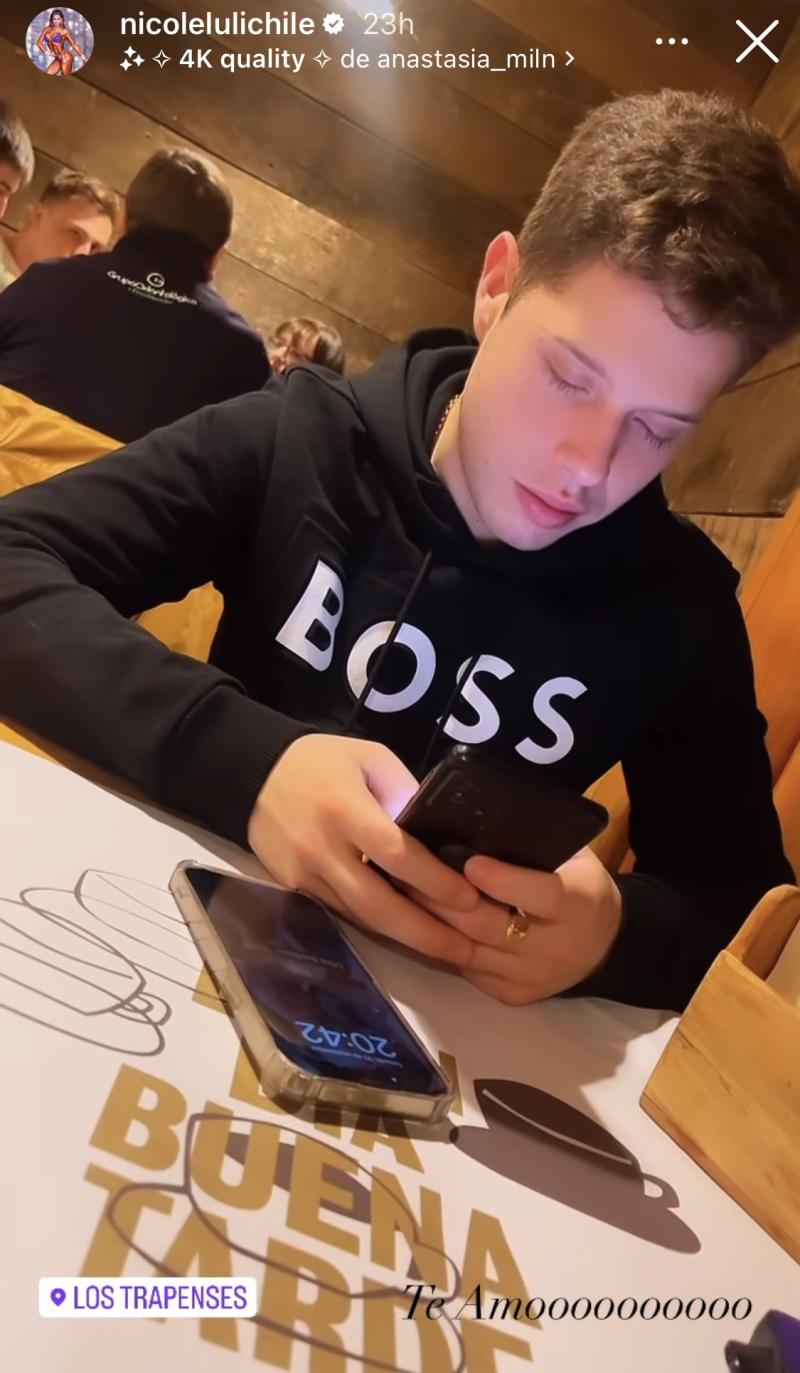 Francisco Moreno mirando su celular sentado frente a Nicole